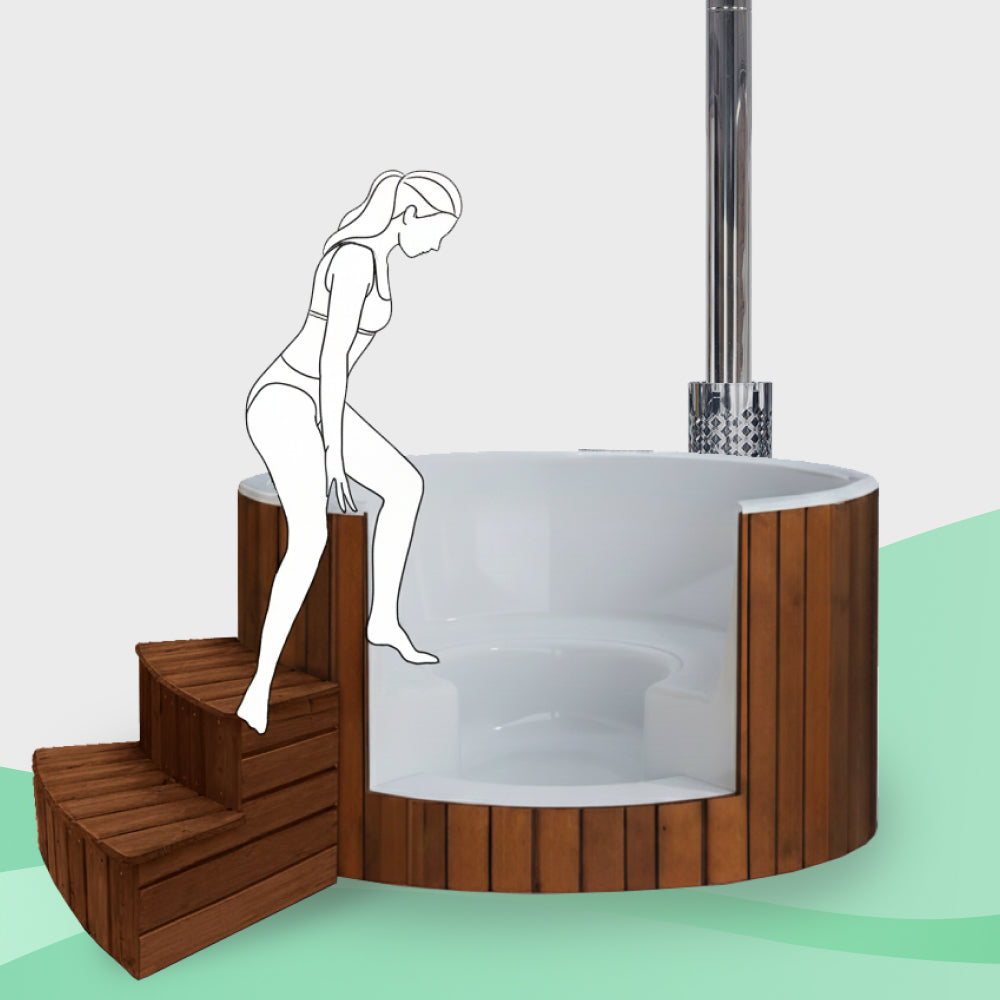 Side view of round wood-fired hot tub with white interior, wooden exterior, metal chimney, and wooden steps with female figure stepping in