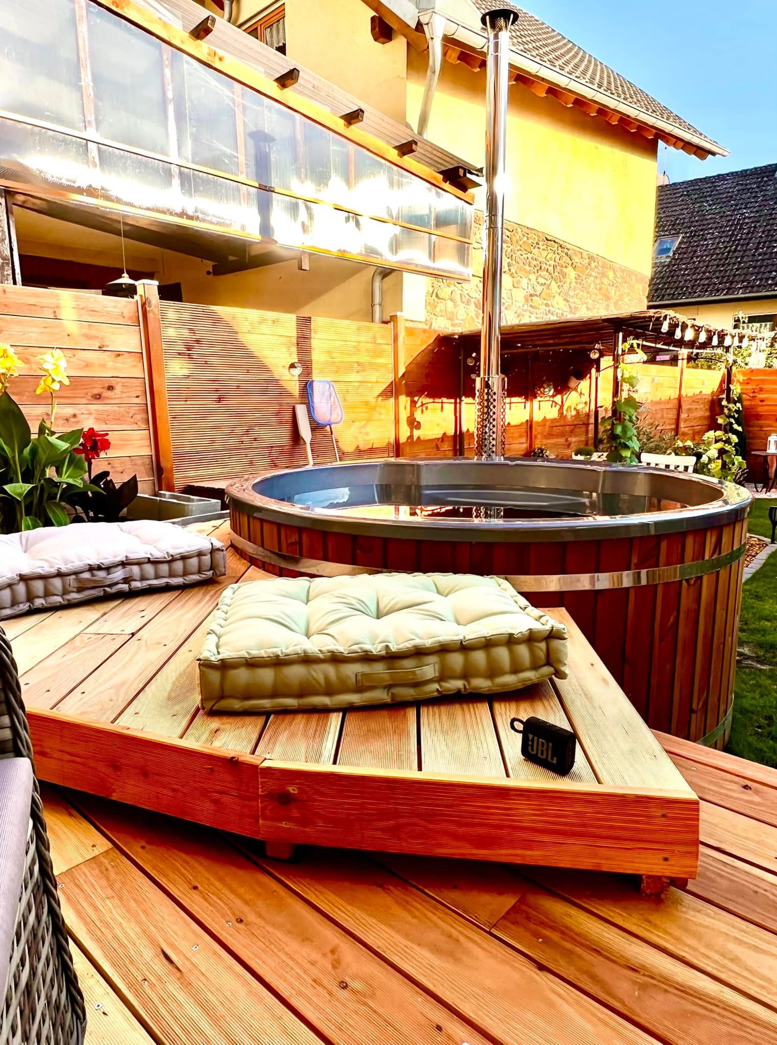 Gardenvity wood fired hot tub on raised wooden decking with cushions and modern backyard decor